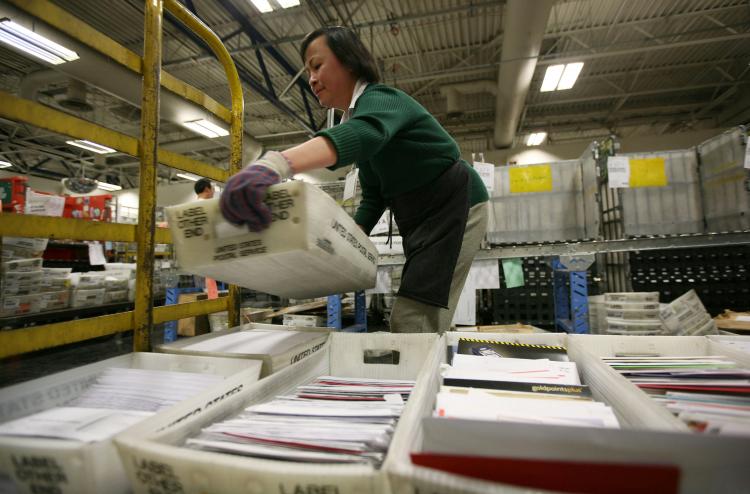 A U.S. Postal worker moves boxes of letters and cards at the U.S. Post Office sort center December 15, 2008 in San Francisco, California. The Postmaster General testified to Congress that USPS might have to cut one day from its delivery schedule, due to r (Justin Sullivan/Getty Images)