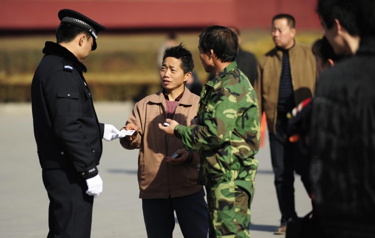 A policeman checks a visitor's ID card at Tiananmen Gate in Beijing on March 1, 2009.      (Peter Parks/AFP/Getty Images)