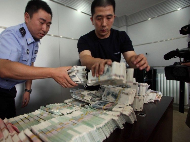 Chinese police officers present counterfeit yuan notes