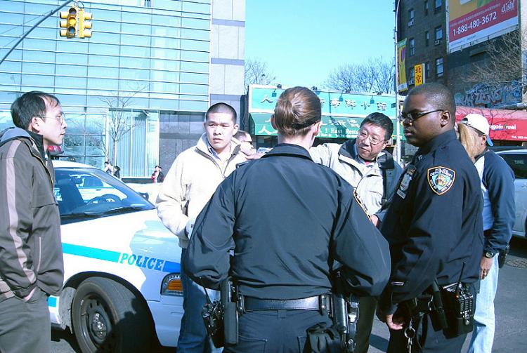 Police talk to Bian He Xiang (between police officers) on Wednesday before arresting him. Bian says he was framed. (The Epoch Times)