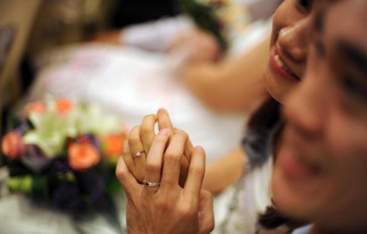 A newly-wed couple gesture after exchanging wedding rings during a mass wedding ceremony at Thean Hou temple in Kuala Lumpur on September 9, 2009. Yet not all Chinese couples can be so open about their relationship. (Saeed Khan/AFP/Getty Images)