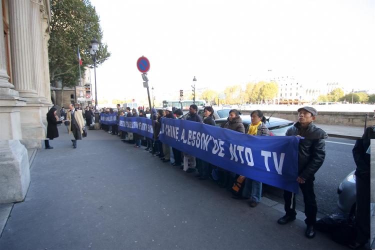 New Tang Dynasty Television (NTDTV) supporters hold banners outside the Paris Commerce Court to support the restoration of NTDTV's broadcast to China. (Ye Xiaobin/The Epoch Times)