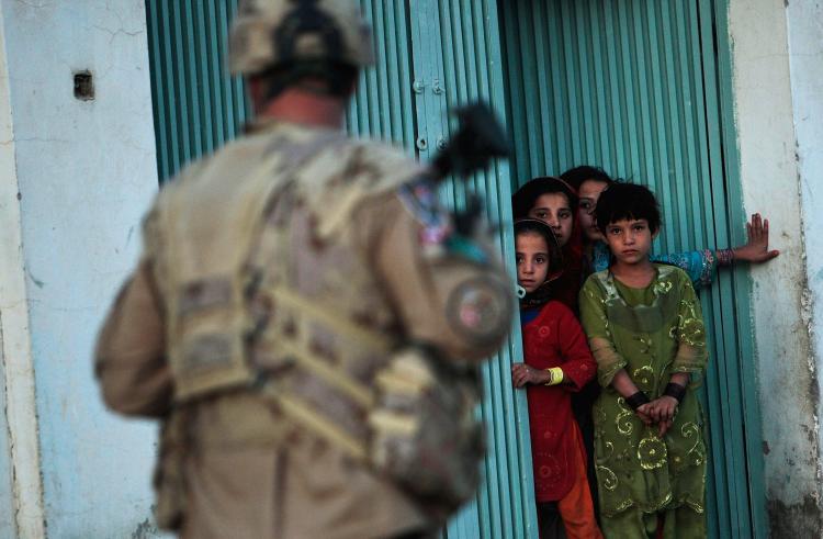 Afghan children watch a Canadian army soldier during a dusk patrol on Oct. 22, 2009 in Kandahar. Adolescents in military families tend to experience additional stress, isolation, and depression after a parent is deployed to Afghanistan, a new study finds. (Chris Hondros/Getty Images)