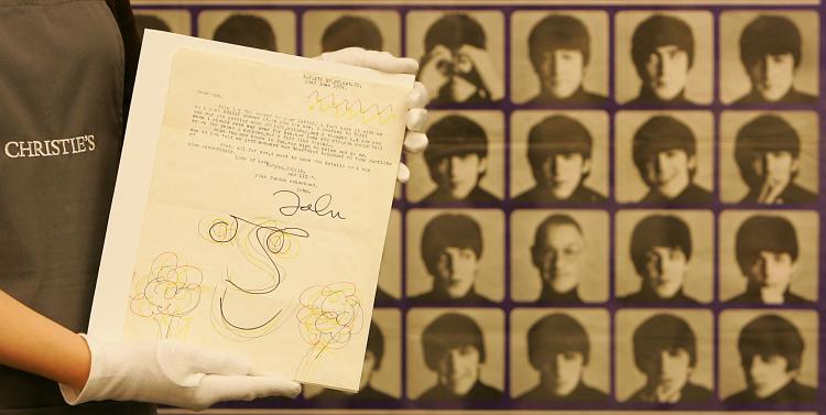 A porter holds a letter from the late ex-Beatle John Lennon at Christie's auction house in London, 22 May 2006. (AFP PHOTO/ODD ANDERSEN)