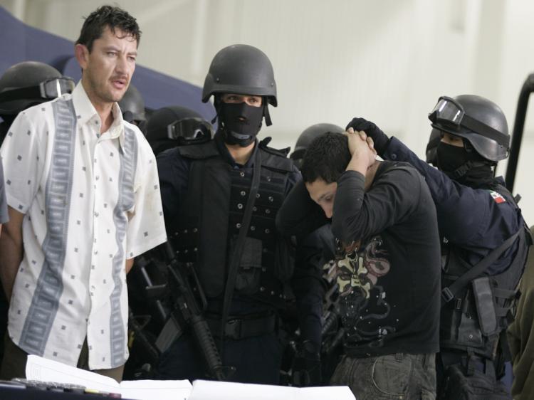 Alleged drugdealers of the 'El Chiquilin' gang of the Sinaloa Cartel are escorted by policemen during their presentation by the Federal Police in Mexico City on February 9, 2010, following their arrest in La Paz, Baja Calfornia state, Mexico.  (STR/AFP/Getty Images)
