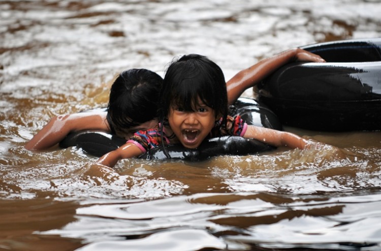 Children paddle with an inflatable ring through floodwaters in front of their houses in Jakarta, Indonesia on Feb. 18, 2010. A new bout of flood waters submerged Jakarta on Dec. 24, 2012, affecting so far 10,250 families. BAY ISMOYO/AFP/Getty Images