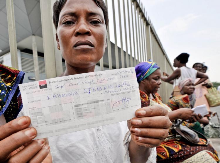 A woman, contaminated by the dumping of toxic waste by the Probo Koala, a Panamanian-registered cargo ship operated by Trafigura in the Ivory Coast in 2006, poses with a check after she received indemnity. (Sai Kambou/Getty Images )