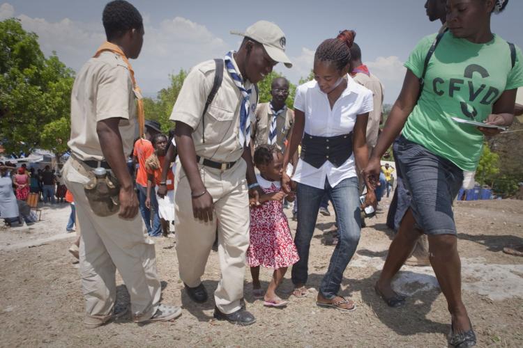 Boy Scouts assist Jimelia Aristide (2nd R) and her family at the Petionville Club camp, as they prepare to be relocated.(Lee Celano/Getty Images)