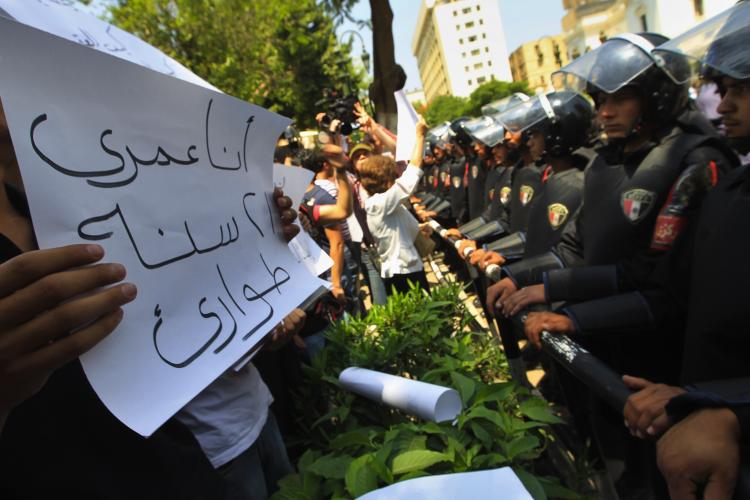 An Egyptian protester holds a sign, which reads in Arabic 'My age is 21 years of emergency' as riot policemen stand guard outside the Parliament building in downtown Cairo during a demonstration against th extension of emergency laws in the country organized by the banned Muslim Brotherhood and other opposition groups on May 11, 2010. (Khaled Desouki/AFP/Getty Images)