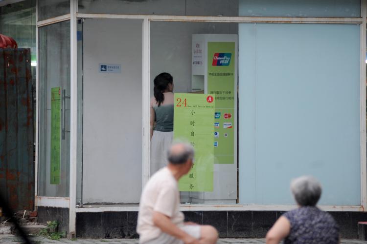 A woman tries to use a fake ATM machine near Guangamen Subway Station in Xuanwu District in Beijing on June 19. (The Epoch Times Photo Archive)