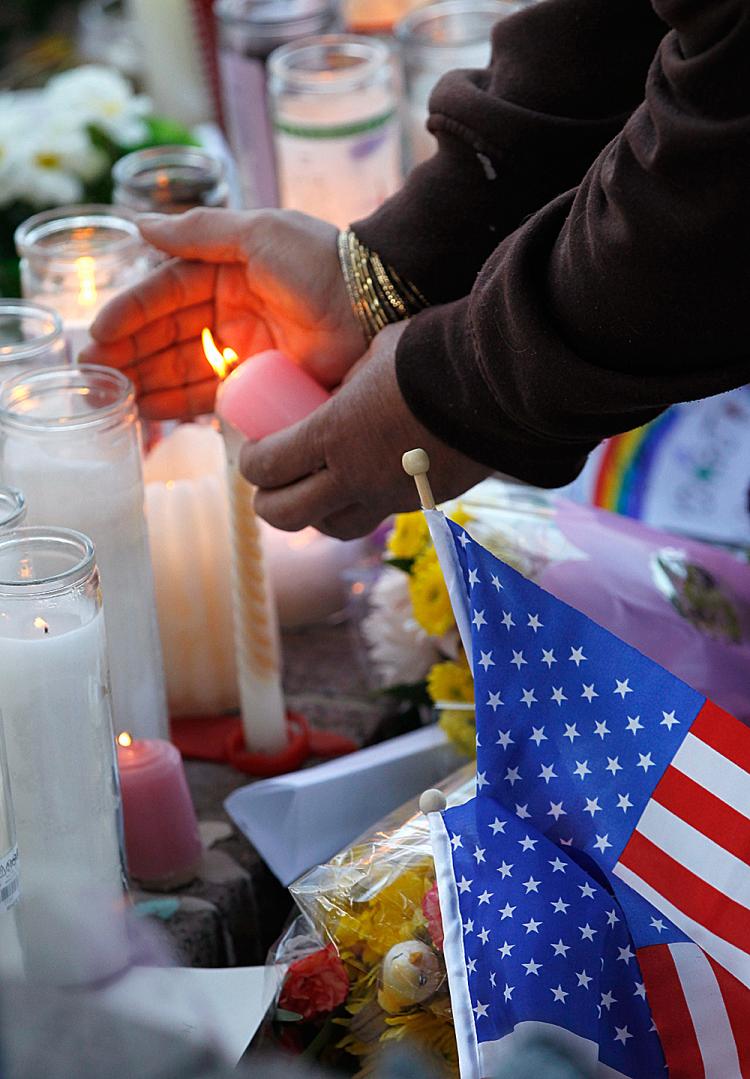 REMEMBERED: A woman lights a candle at a makeshift memorial near the district office of U.S. Rep. Gabrielle Giffords (D-Ariz.), a day after a gunman allegedly opened fire during a public event titled Congress on your Corner outside a grocery store in Tucson, Ariz. (Kevin C. Cox/Getty Images)
