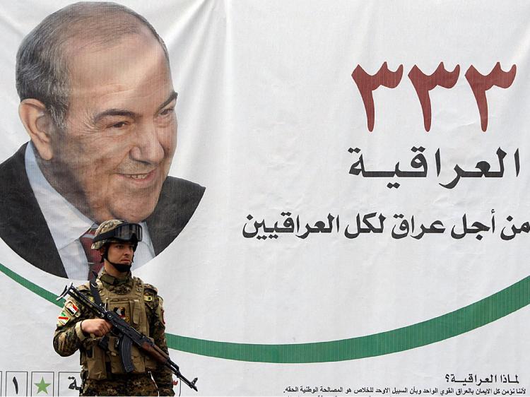 An Iraqi soldier guarding a location of al-Iriqayah secular bloc stands in front of a portrait of former Iraqi premier Iyad Allawi in Baghdad on April 17, 2010. (Ahmad Al-Rubaye/AFP/Getty Images)