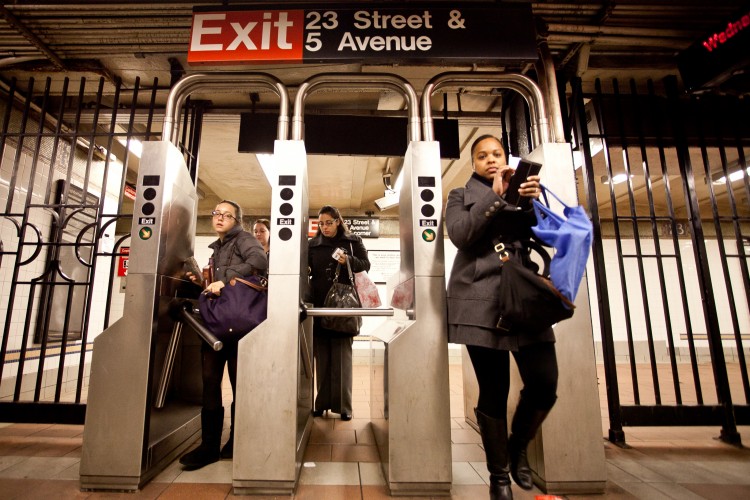 Commuters at the 23rd Street and Fifth Avenue station pass through turnstiles last winter. (Amal Chen/The Epoch Times) 