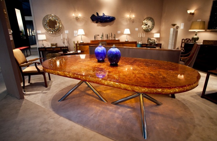 The table (98 inches in width and 50.5 inches in diameter) is a golden, sap-colored, translucent slab supported by a steel base. (Amal Chen/The Epoch Times)