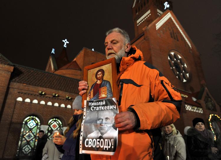 A man holds an icon and a poster depicting Mikola Statkevich, a presidential candidate, who was jailed after last month's controversial vote, reading 'Free Statkevich!' in Minsk, on Jan. 19, marking one month after the election. Following the Dec. 19, 2 (Viktor Drachev/AFP/Getty Images)