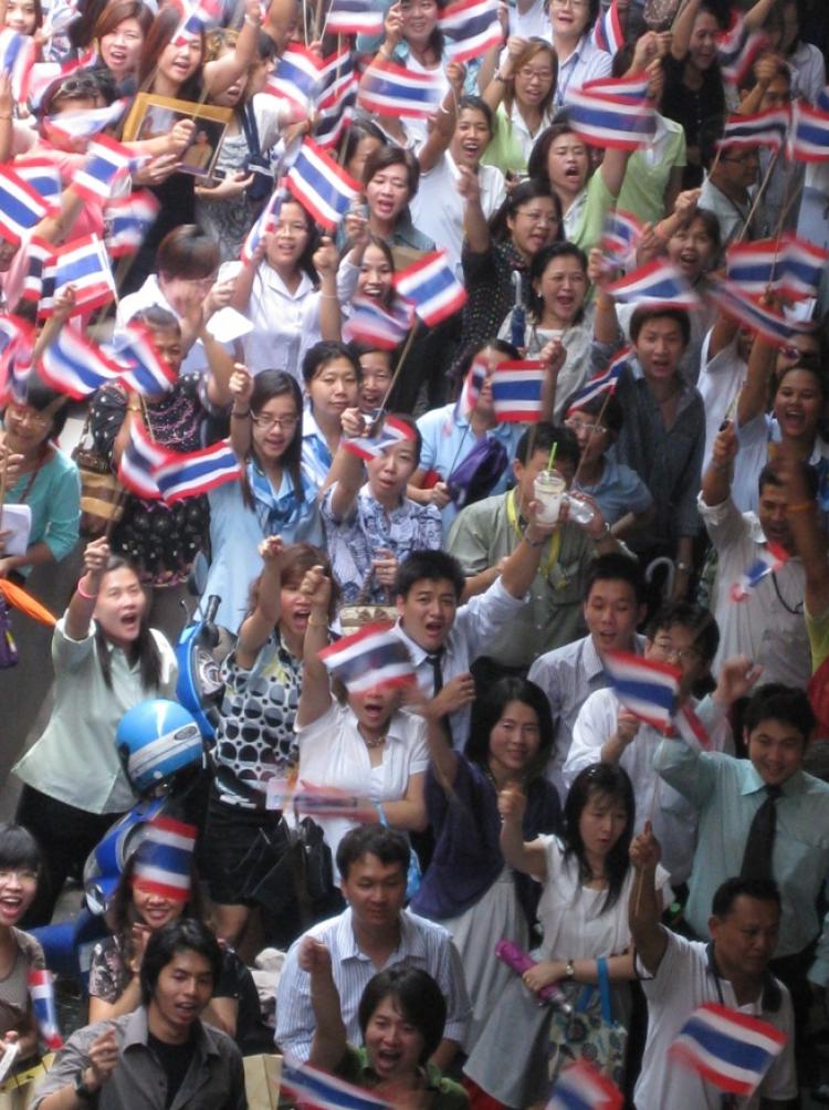 COUNTERPROTEST: Office workers on their lunchbreak wave Thai national flags in a pro-government rally in Bangkok's Silom Road which is under threat from being occupied by anti-government red shirt protesters.(James Burke/The Epoch Times )