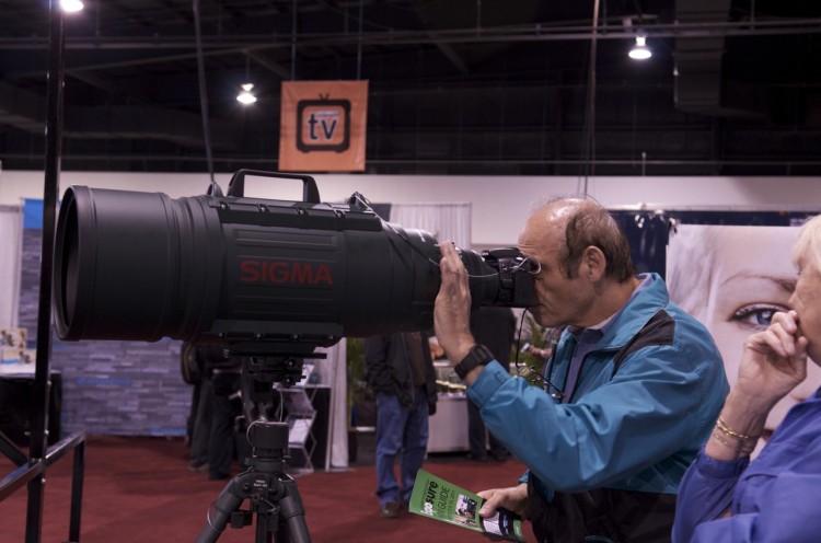 A man looks through Sigma's massive 200mm-500mm F2.8 EX DG, DSLR telephoto lens. (Matthew Little/The Epoch Times)