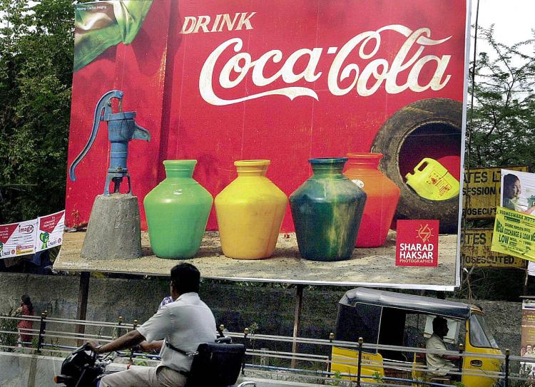 DRINK UP, PAY UP: Commuters pass a Coca-Cola billboard in Chennai, India. A new tax proposal by President Barack Obama would force multinational companies to pay higher taxes on overseas profits.  (AFP/Getty Images)