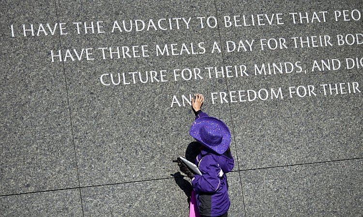 A young girl touches the quote at the Martin Luther King Jr. Memorial