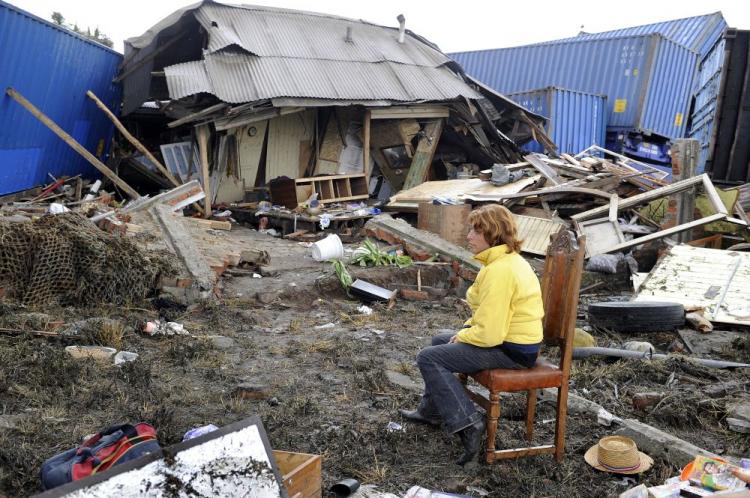 A woman guards the few belongings she has left after civil unrest and mass lootings in Talcahunao, 12.5 miles from Concepcion; in the background containers are seen scattered amid houses from a tsunami caused by the massive earthquake on Feb. 27. (Daniel Garcia/AFP/Getty Images)