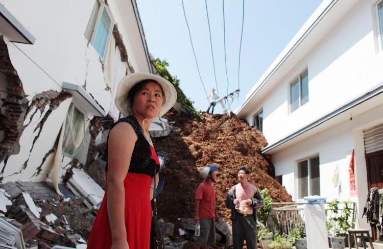 WORST MAY STILL COME: A Chinese woman looks at buildings damaged by a flood-triggered landslide in southwest Sichuan Province's Hanyuan County on July 27. The landslide left 21 people missing as torrential rains forced officials to shut boat traffic throu (STR/AFP/Getty Images)