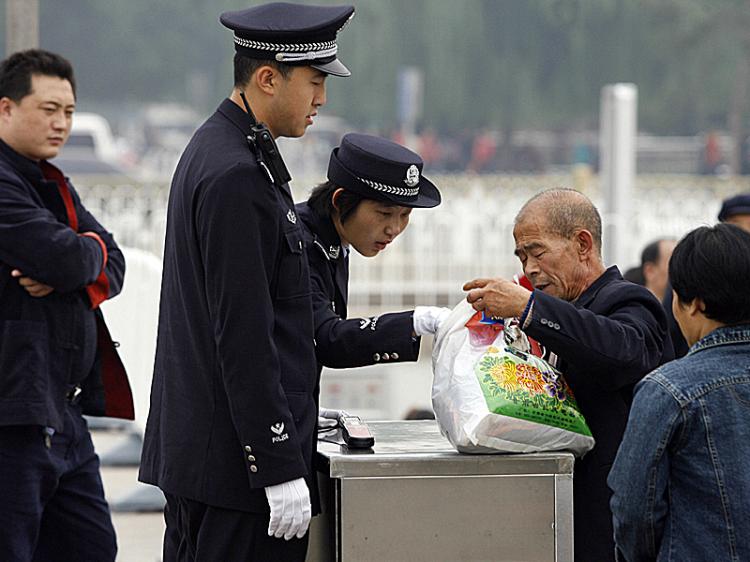 A policewoman checks a man's bag on Tiananmen Square in Beijing. Intense security measures are already in place for next month's Beijing Olympics.  (Peter Parks/Getty Images)