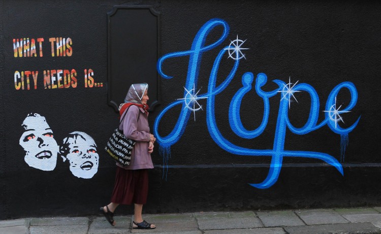 HOPE: In a file picture taken on November 25th, 2011, a woman walks past a wall covered in graffiti, which reads 'What This City Needs Is Hope' on a building in Dublin, Ireland.