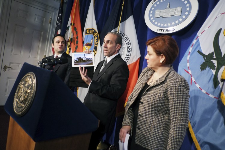 New York City Councilmember James Oddo holds an iPad with a photo of an elevated house constructed without stairs, while Speaker Christine Quinn and Councilmember Vincent Ignizio look on. Oddo and Ignizio will introduce legislation to help prevent problems like this from occuring in New York City. (William Alatriste/New York City Council)