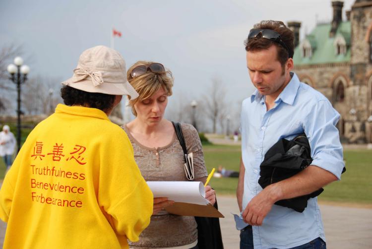 Tourists on The Hill signing a petition (Samira Bouaou/Epoch Times)