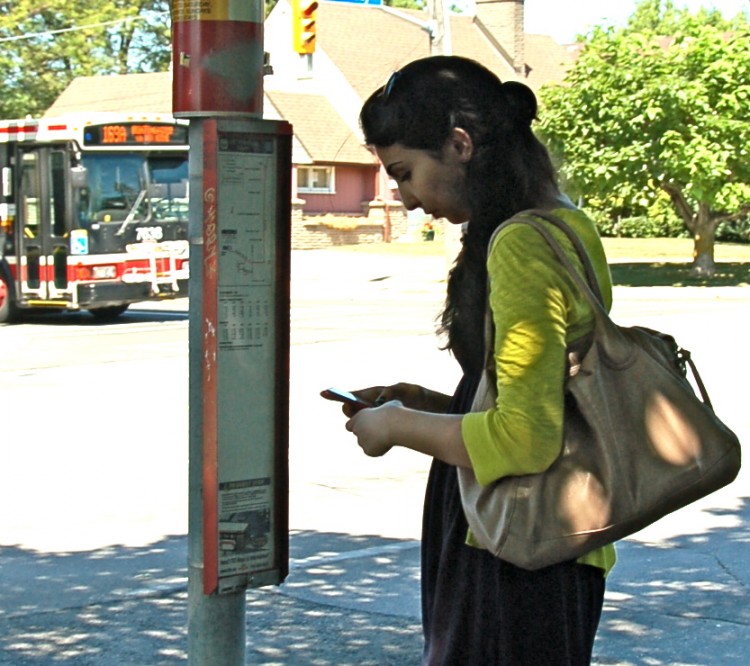 Sam Kokabi waits for her bus at the Pharmacy/Huntingwoodbus station on Tuesday July 12.   (Snow Mei/The Epoch Times)