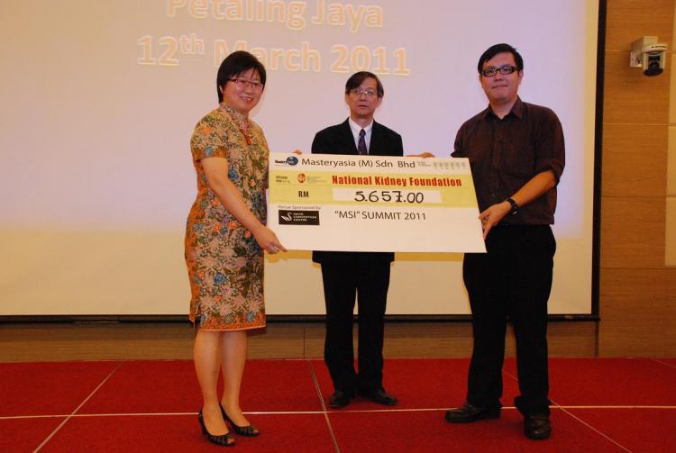 Ms Ch'ng (Left) and Mr See (Middle) presented a RM5,657 check to a representative from NKF.  (The Epoch Times)