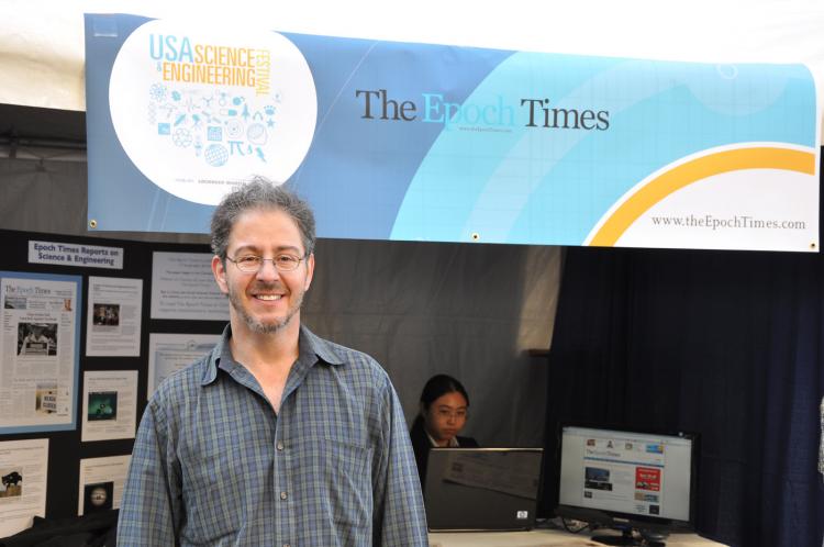 Comedian Brian Malow poses in front of the Epoch Times booth at the Wilson Plaza in Washington, D.C. on Oct. 23. (Du Won Kang/The Epoch Times)