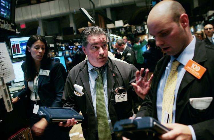 Traders talk on the floor near the end of the trading day at the New York Stock Exchange yesterday. Stocks closed down more than 700 points on Wednesday.  (Chris Hondros/Getty Images)