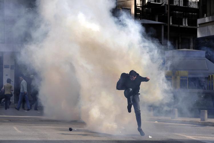 A demonstrator kicks a tear gas canister in Athens on March 11, during the 24-hour general strike to protest the government's austerity plan to solve the country's debt crisis. Violence erupted, with riot police firing tear gas at hooded youths hurling fi (Aris Messinis/AFP/Getty Images)
