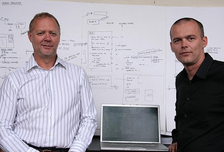 Green printer co-owners Brian Schindel and Alen Rokolj pose in front of a software programming map. The pair aim to revolutionize the printing industry with their software by making it easier for companies to implement green technologies. (Andrea Hayley)