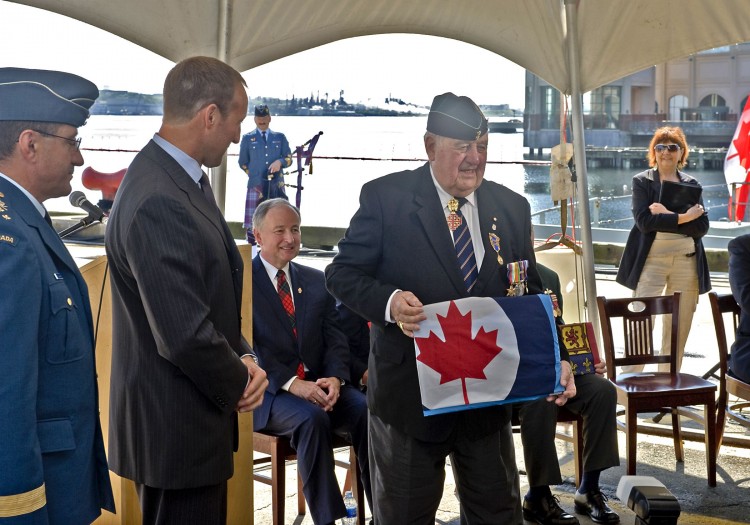 Defence Minister Peter MacKay (C), and Chief of the Air Staff Lieutenant-General Andre Deschamps (L), present Flight Sergeant Michael Nash Kelly with the historical Ensign of the Royal Canadian Air Force on Tuesday in Halifax. (Courtesy National Defence)