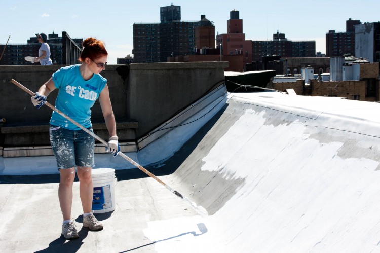 COOLING OFF: A volunteer paints the roof of 65 E. Fourth St. white on Monday afternoon.  (Tara MacIsaac/The Epoch Times)