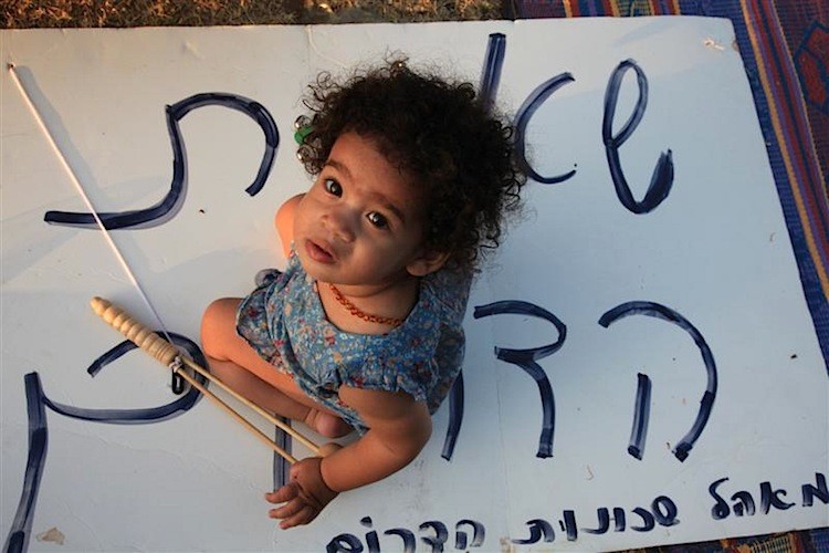 A girl sits on a sign that reads 'the south encampment.' The image is part of an exhibit and a recently published book by photojournalist Yaira Yasmin. (Yaira Yasmin/The Epoch Times)