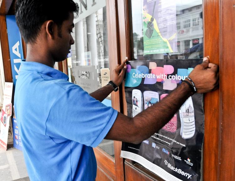 CHANGE IN POLICY: An Indian salesman changes a poster of Blackberry at a shop in New Delhi on Aug. 5. On Tuesday Blackberry producer, Research in Motion, agreed to provide the Indian government with certain types of data of its Indian customers.  (Prakash Singh/Getty Images)