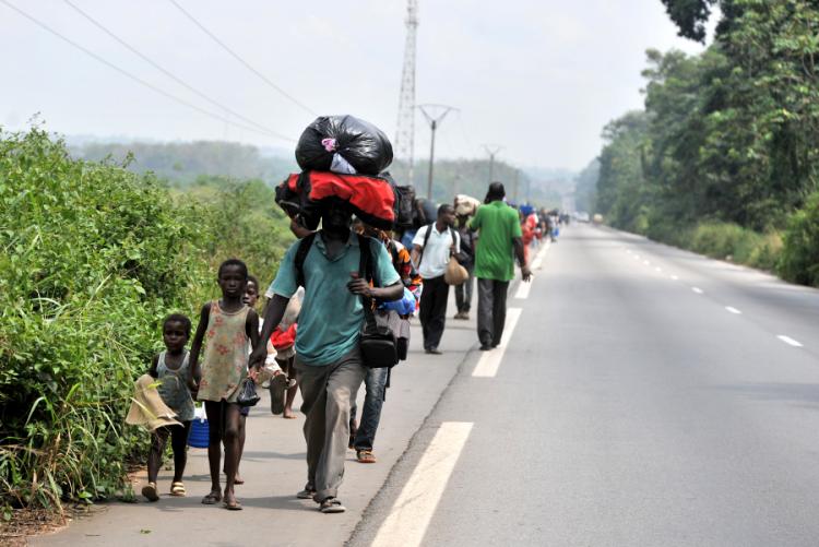 A family flees the neighbourhood of Abobo PK 18, a suburb of Abidjan, carrying luggage on their heads, on February 24, 2011. (Issouf Sanogo/AFP/Getty Images)