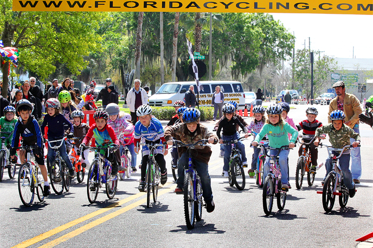 A couple of dozen children ages four to nine leave the starting line to begin the Chain of Lakes Cycling Classic Kids' Race. (James Fish/The Epoch Times)