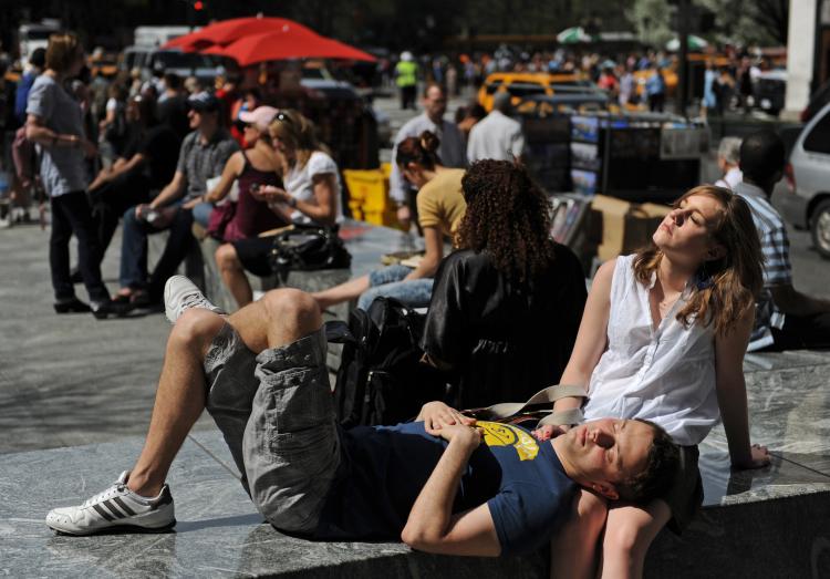 A couple enjoys the afternoon sun on an unusually warm spring day near the Plaza Hotel on Fifth Avenue and 59th Street on Wednesday. The temperature in Central Park reached a record high of 91 degrees by mid-afternoon. (Stan Honda/AFP/Getty Images)