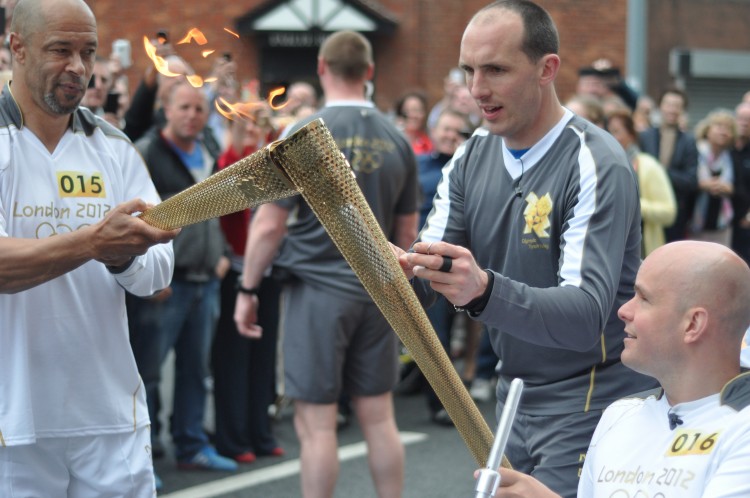 Former Ireland and Manchester United midfielder Paul McGrath passing the Olympic flame to Mark Pollock, on Dublin's Macken StreeT
