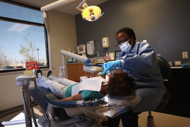 Registered dental hygienist Denise Lopez-Rodriguez cleans teeth at a community health center in Aurora, Co., in March. The center, called the Metro Community Provider Network, has received some 6,000 more Medicaid eligible patients since the healthcare reform law was passed in 2010. (John Moore/Getty Images)