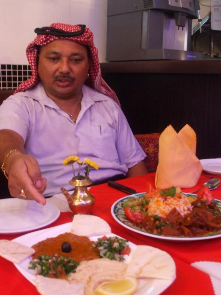 Mr. Bahadur Shiva with his Lamb Quzi, Biryani Chicken and Biryani Laham.  (Oliver Perrett/The Epoch Times)