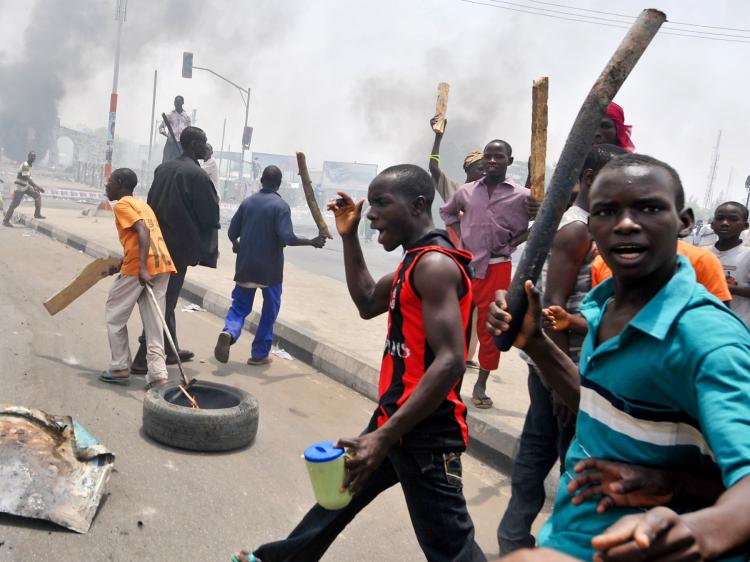Youths hold wooden and metal sticks while running battles broke out between protesters and soldiers in Nigeria's northern city of Kano, on April 18,  as President Goodluck Jonathan headed for an election win.  (Seyllou Diallo/Getty Images)