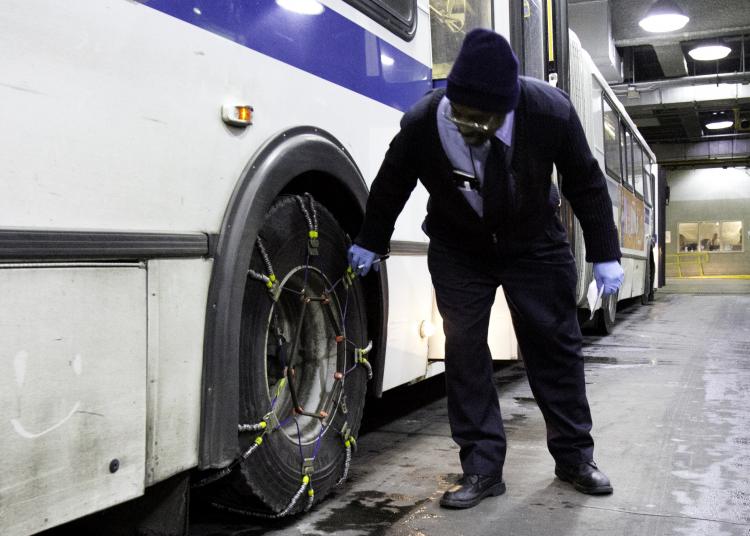 FINAL CHECK: MTA Bus driver David Kemp does a final check of his bus before it hits the road Tuesday. Up to 12 inches of snow have been predicted.  (Phoebe Zheng/The Epoch Times)
