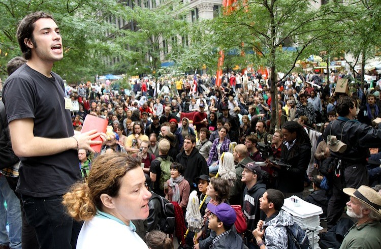 A young man and woman act as part of the people's mic, which involves repeating the speakers words so a large crowd can hear, at a general assembly meeting on Oct. 13 in Zuccotti Park (Zack Stieber/The Epoch Times)