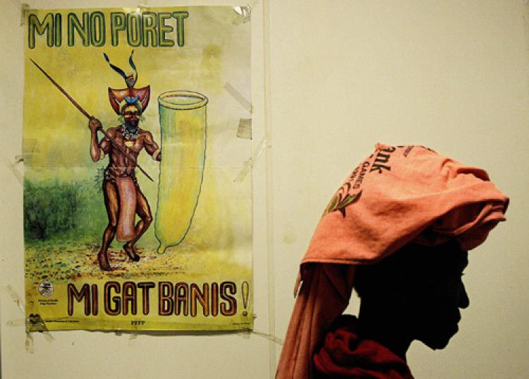 A woman passes an AIDS awareness poster featuring an Enga warrior using a condom as a shield, with the words: 'I'm not afraid. I have protection!' (Torsten Blackwood/AFP/Getty Images)