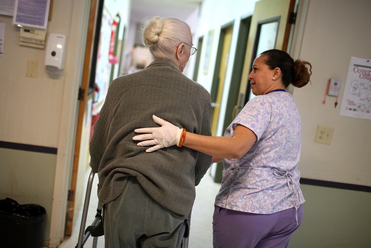 A program assistant at an adult care center helps her elderly patient